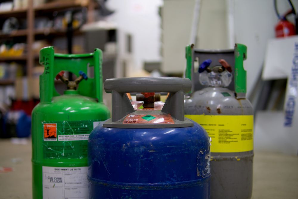 Three Different Colored Refrigerant Tanks With Valves, in a Workshop Setting — Industry Fire Services in Ayr, QLD