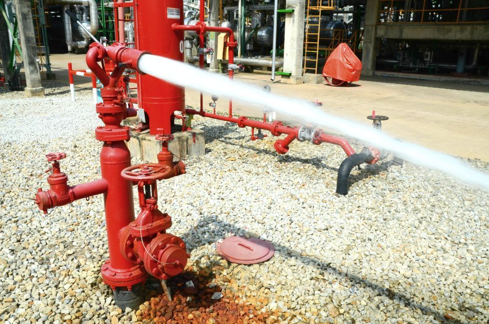 Red Fire Hydrant Spraying Water at an Industrial Site — Industry Fire Services in Bowen, QLD