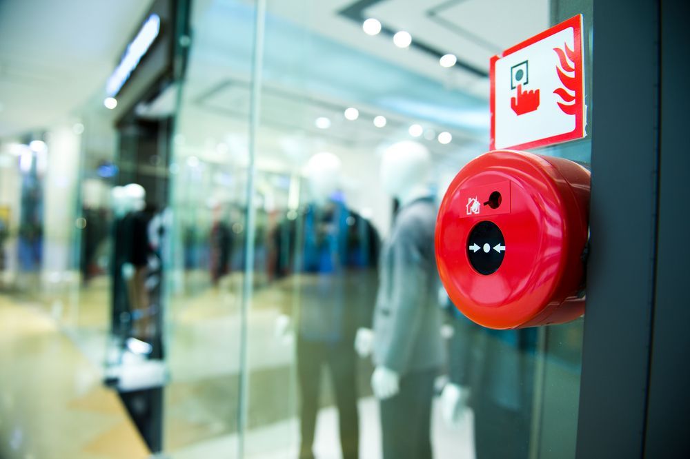 Red Fire Alarm Next to a Glass Store Entrance — Industry Fire Services in Charters Towers, QLD