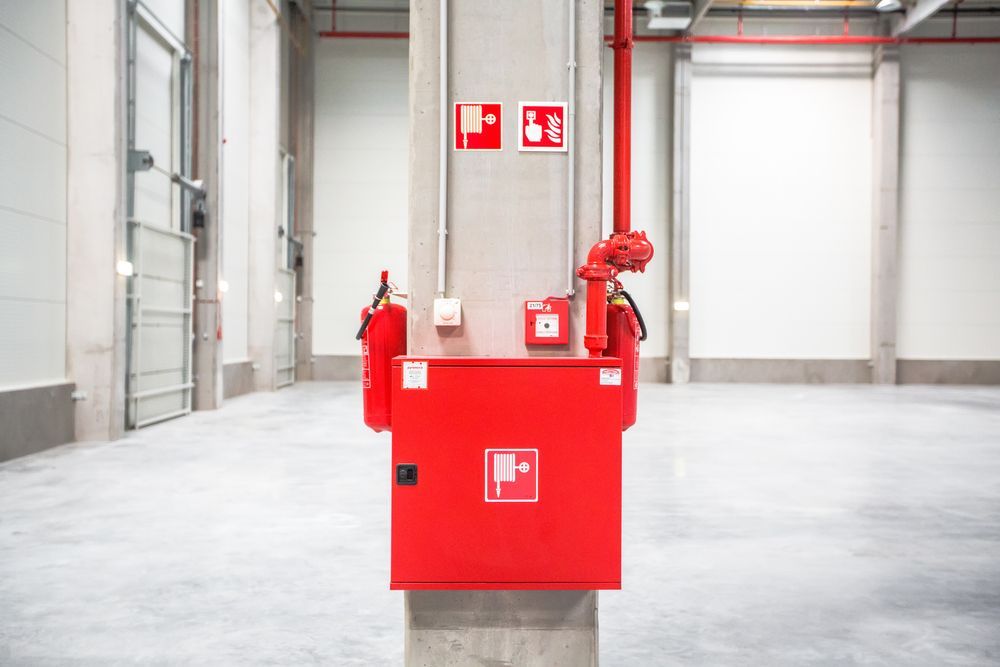 Red Fire Safety Equipment on a Concrete Pillar in a Warehouse — Industry Fire Services in Port Douglas, QLD