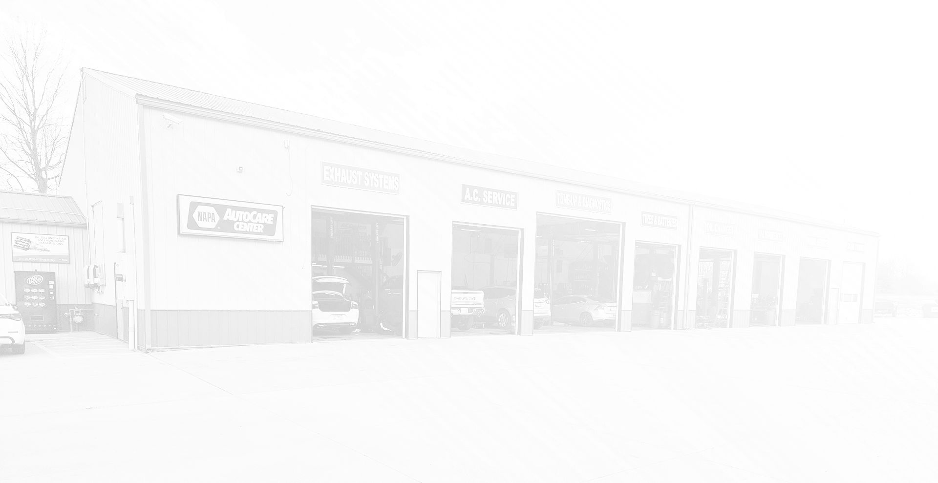 Garage building with multiple bays, cars visible, overcast day. | Z-1 Automotive, Inc.