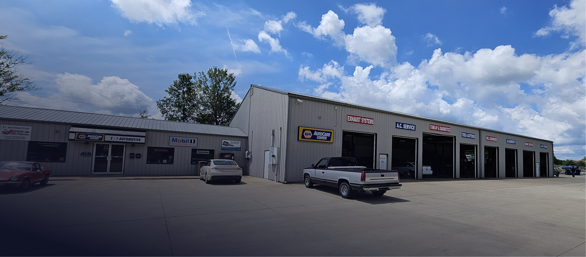 Auto repair shop with several bays under a blue sky with clouds. | Z-1 Automotive, Inc.