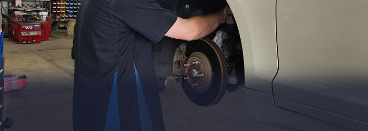 Mechanic working on a car brake rotor in a shop. | Z-1 Automotive, Inc.