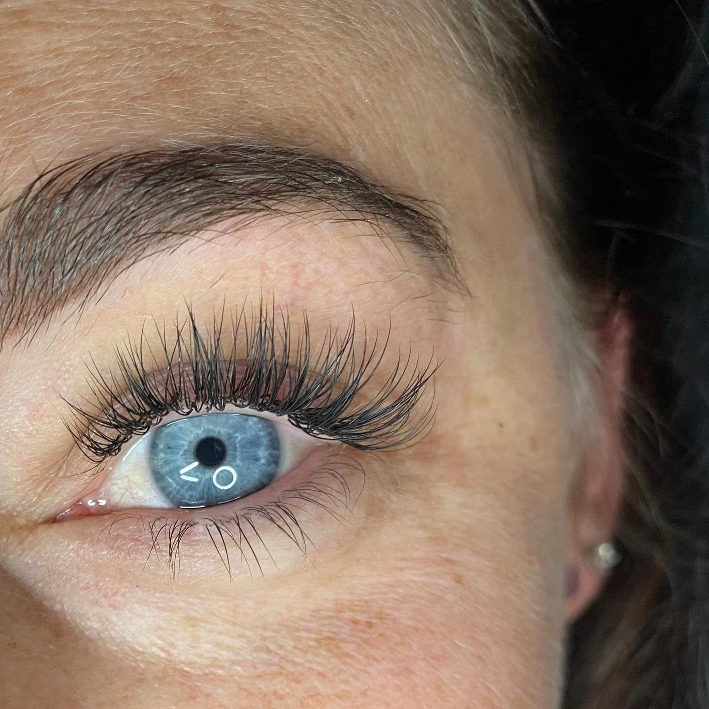 A close up of a woman 's blue eye with long eyelashes.