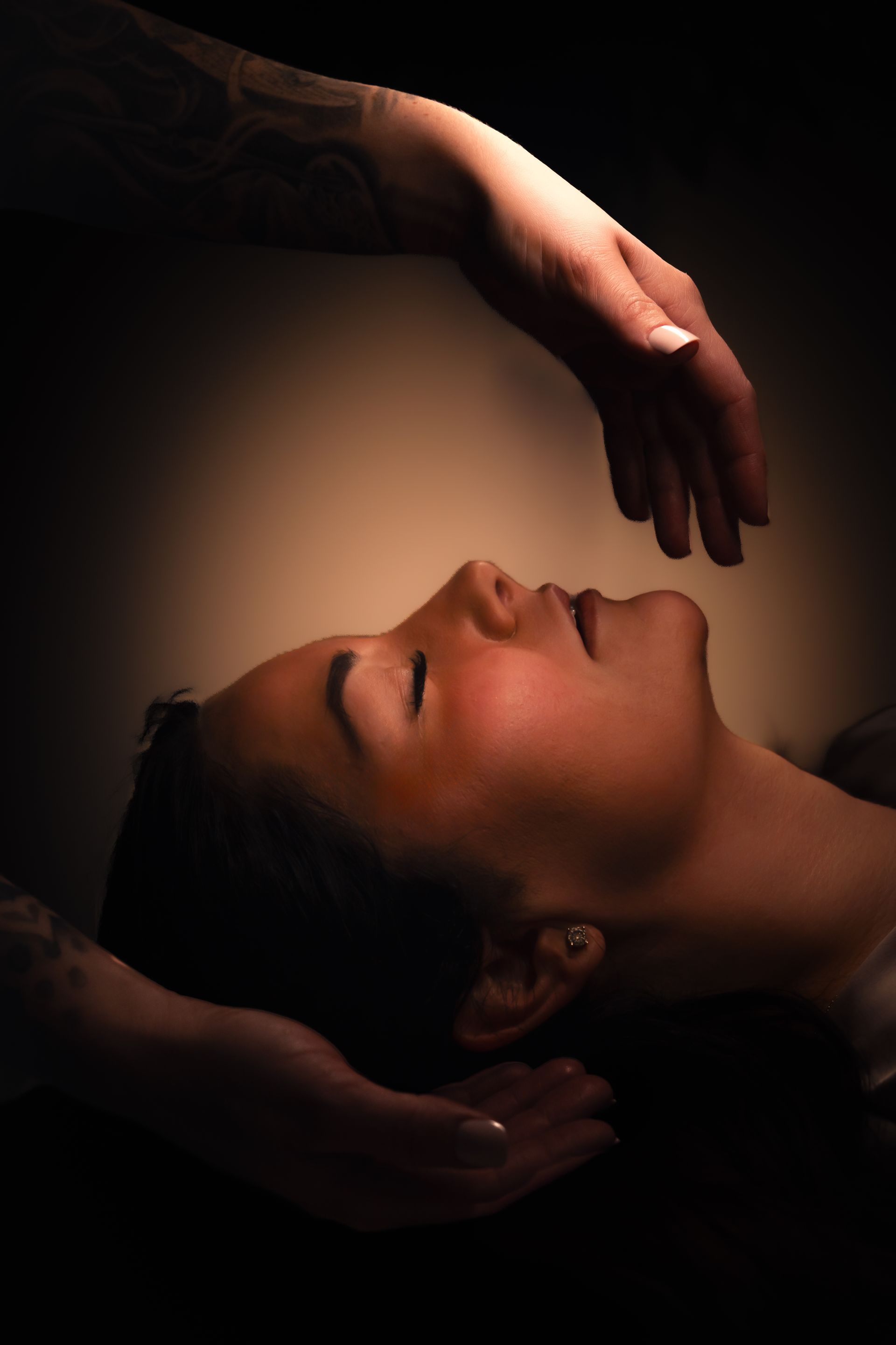 A woman is laying on a bed getting a head massage.