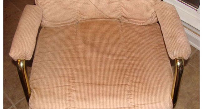 A tan corduroy armchair with metallic gold-tone armrest supports, viewed from above against a tile floor.