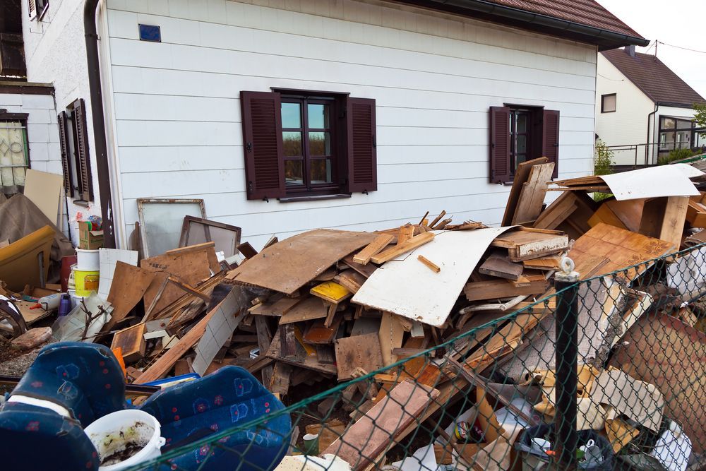 A White House With Brown Shutters Has a Large Pile of Wooden Debris — Smiley Rubbish Removal In Wauchope, NSW