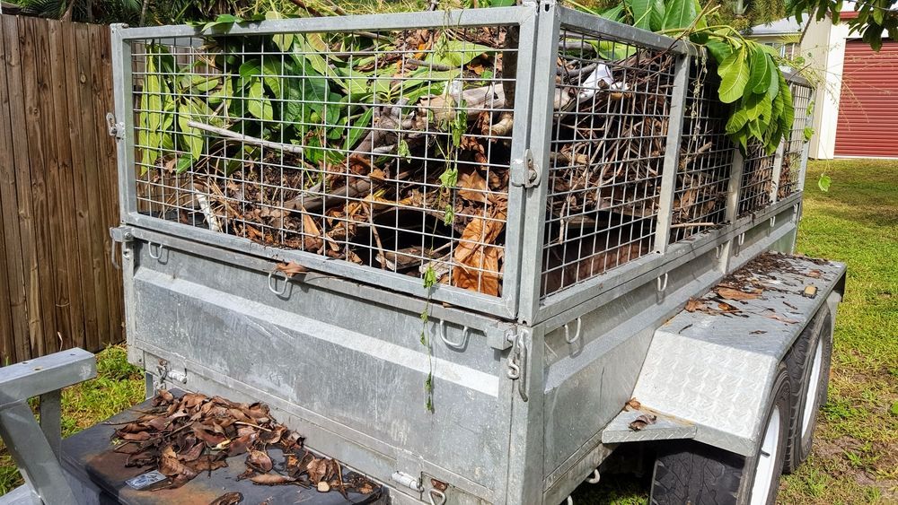 A galvanized metal cage trailer filled with garden waste, leaves, and branches — Smiley Rubbish Removal In Laurieton, NSW