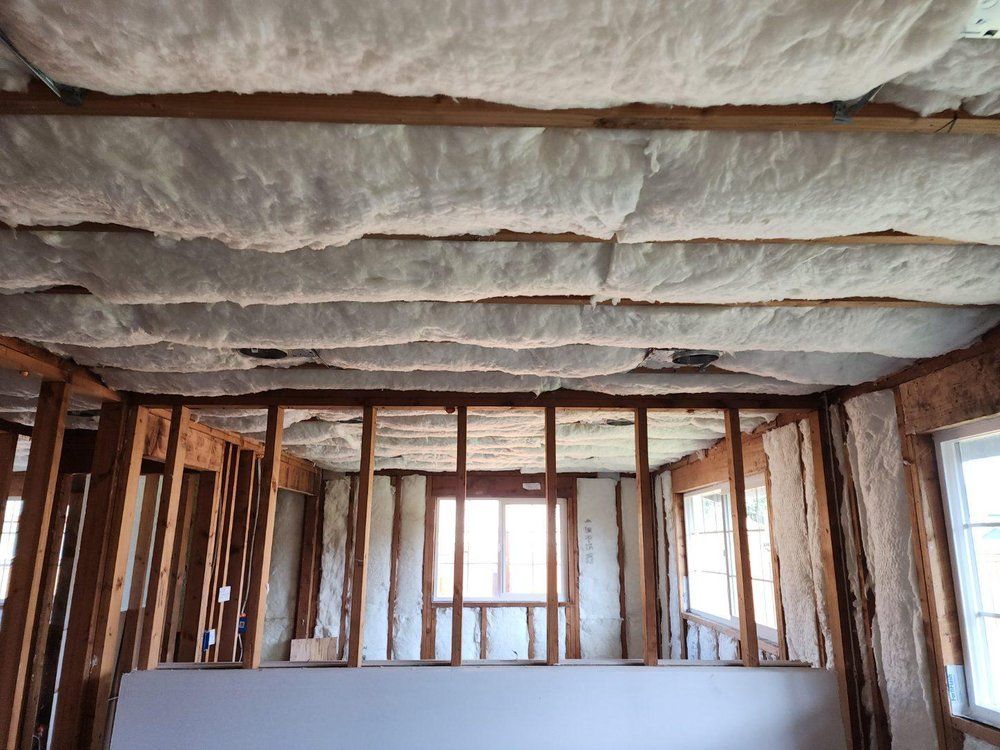 Interior framing with insulation installed in the ceiling and walls. Unfinished construction site.