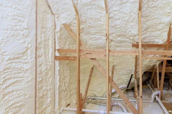 Attic space with spray foam insulation between wooden rafters.