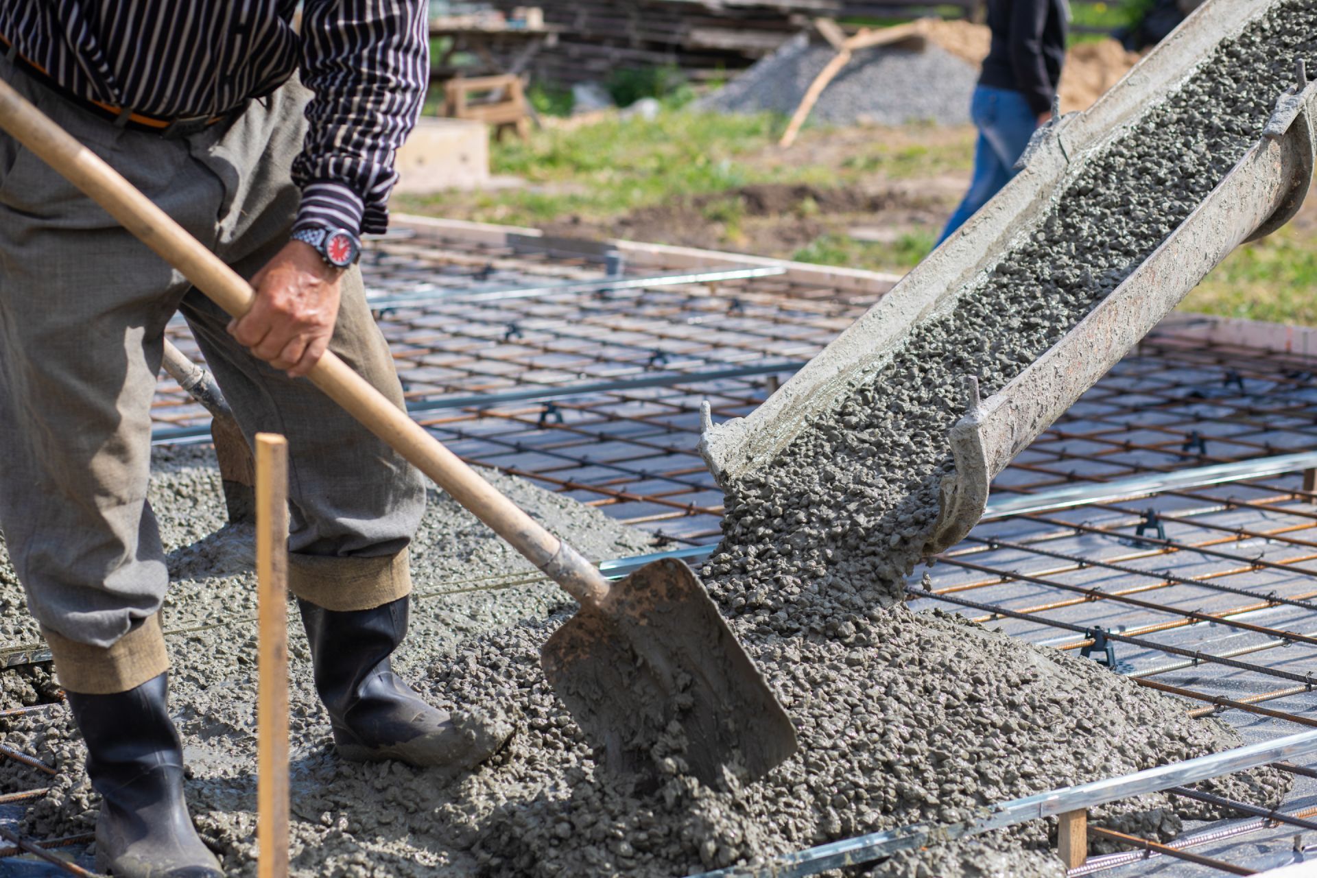 A man is pouring concrete into a foundation with a shovel.
