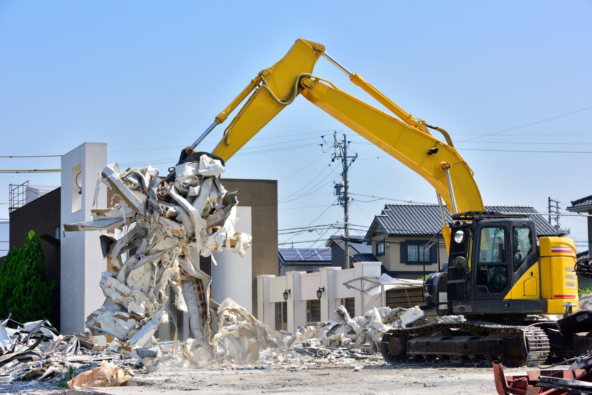 A large yellow excavator is demolishing a building.