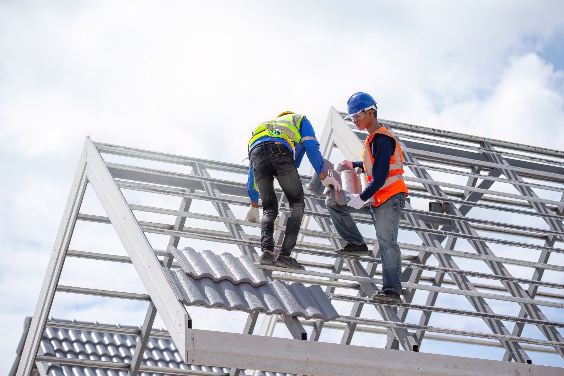 Two construction workers are working on the roof of a building.