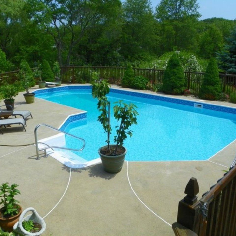 Backyard swimming pool with blue water, lounge chairs, and a patio umbrella.