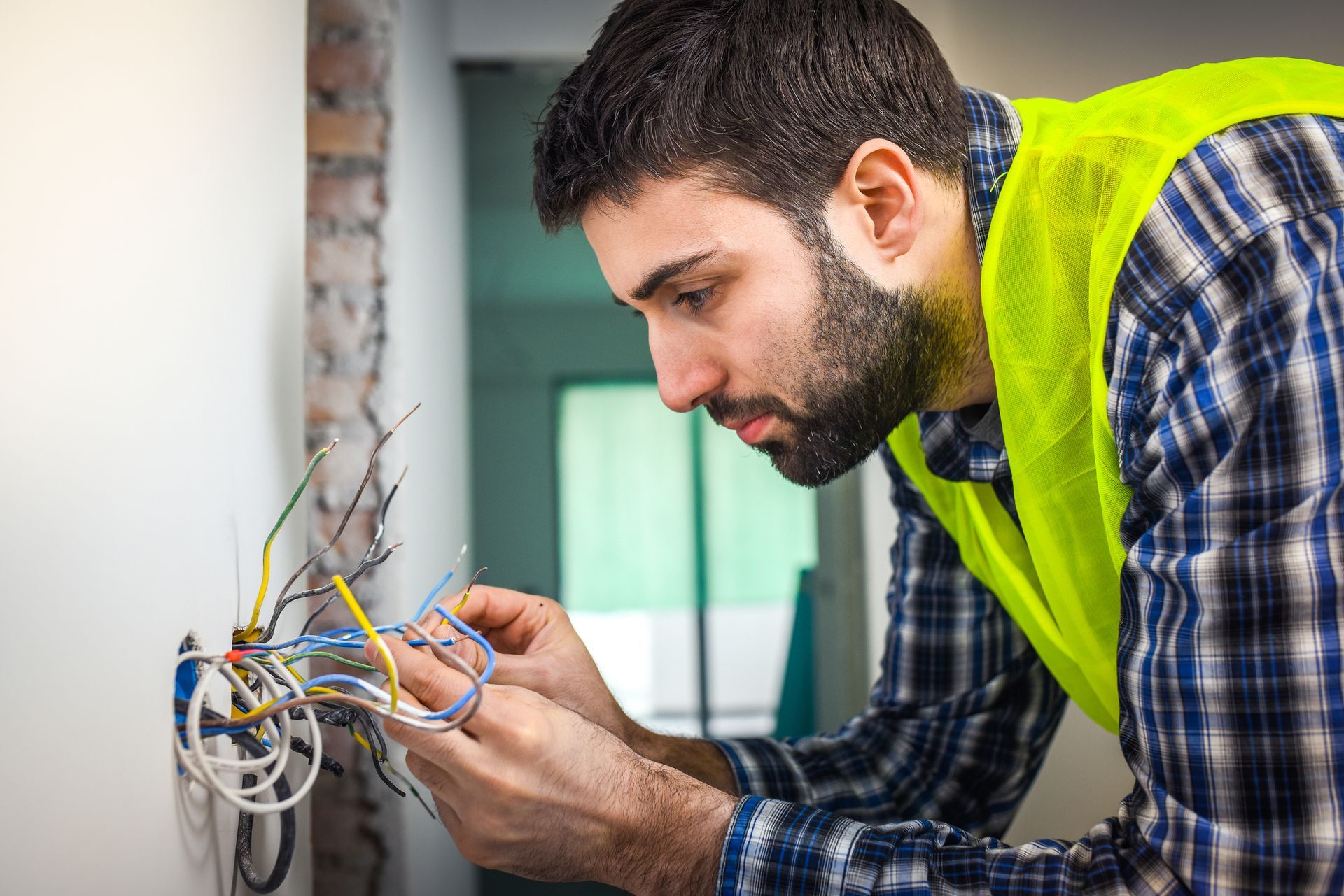 A man is working on an electrical outlet on a wall.