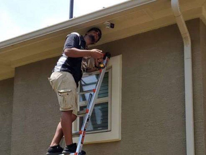 a man installing surveillance camera outside a house