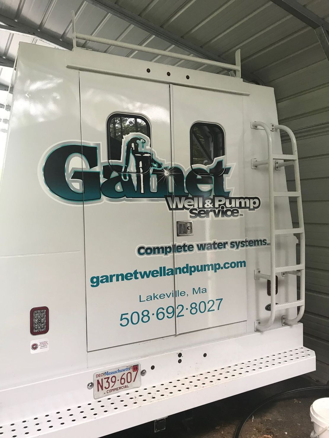 A garnet well and pump service truck is parked in a garage.