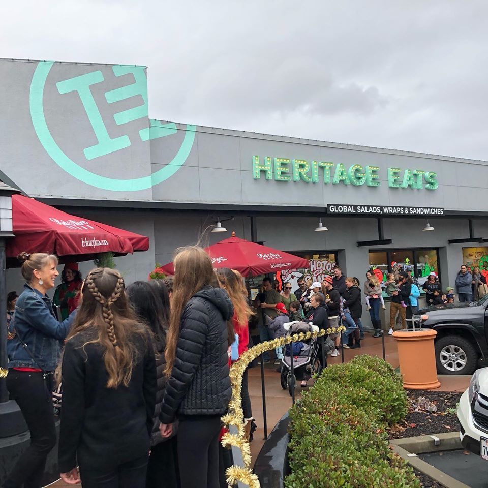 A group of people are standing outside of heritage eats