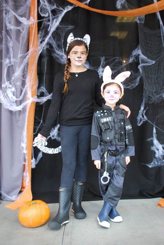 A girl in a cat costume stands next to a boy in a police uniform