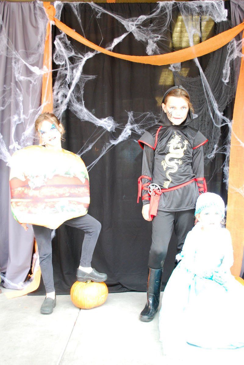 Three children in halloween costumes are posing for a picture