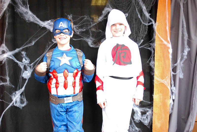 Two children dressed in superhero costumes are standing next to each other.