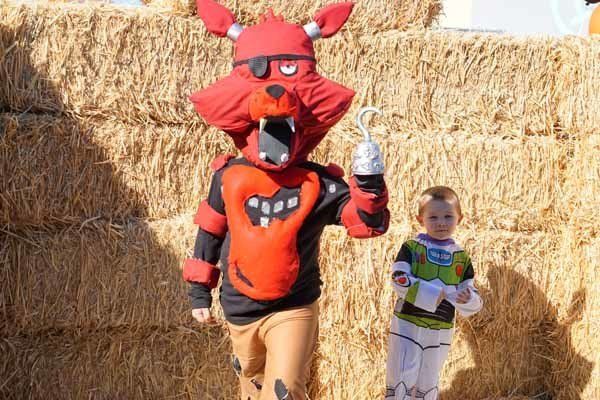 A boy in a foxy costume is standing next to a boy in a buzz lightyear costume.