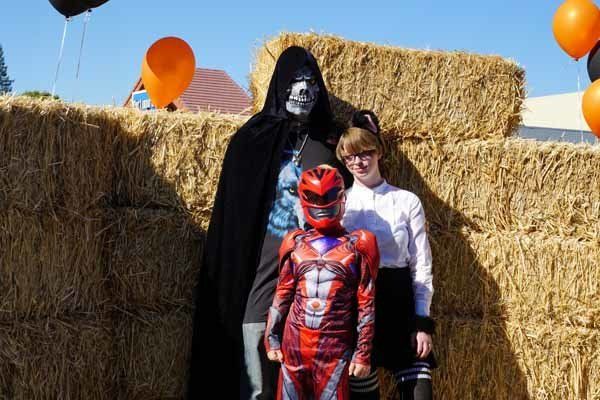A group of people in costumes are posing for a picture in front of hay bales.