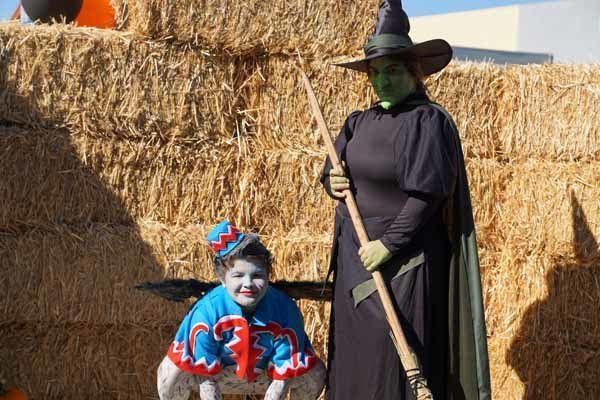 A woman dressed as a witch is standing next to a child dressed as a wizard.