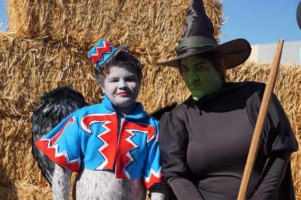 A woman in a witch costume stands next to a boy in a wizard of oz costume
