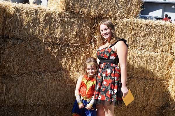 A woman and a child are posing for a picture in front of hay bales.