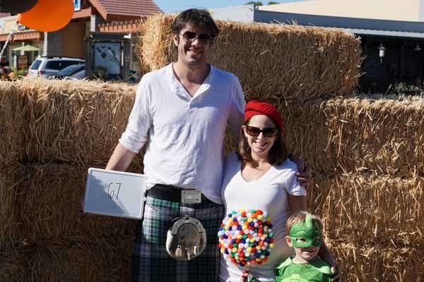 A family is posing for a picture in front of hay bales.