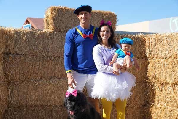 A family is posing for a picture in front of hay bales.