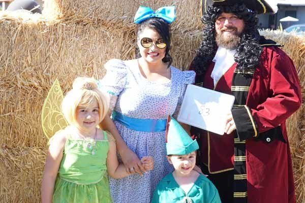 A family posing for a picture in costumes including tinkerbell peter pan and captain hook