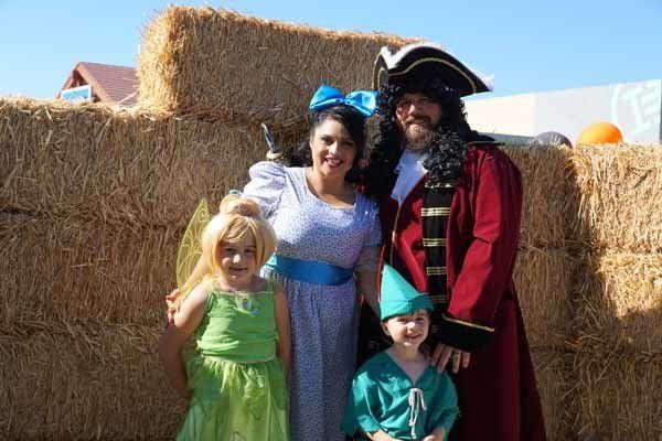 A family is posing for a picture in front of hay bales.
