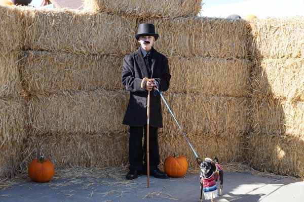 A man in a top hat is standing next to a dog on a leash.