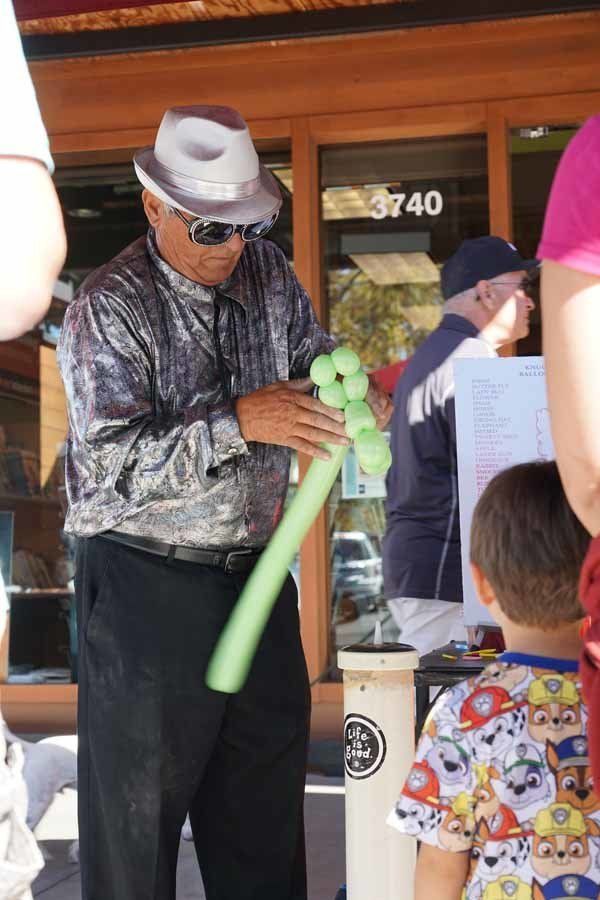 A man is holding a green balloon in front of a building with the number 3740 on it