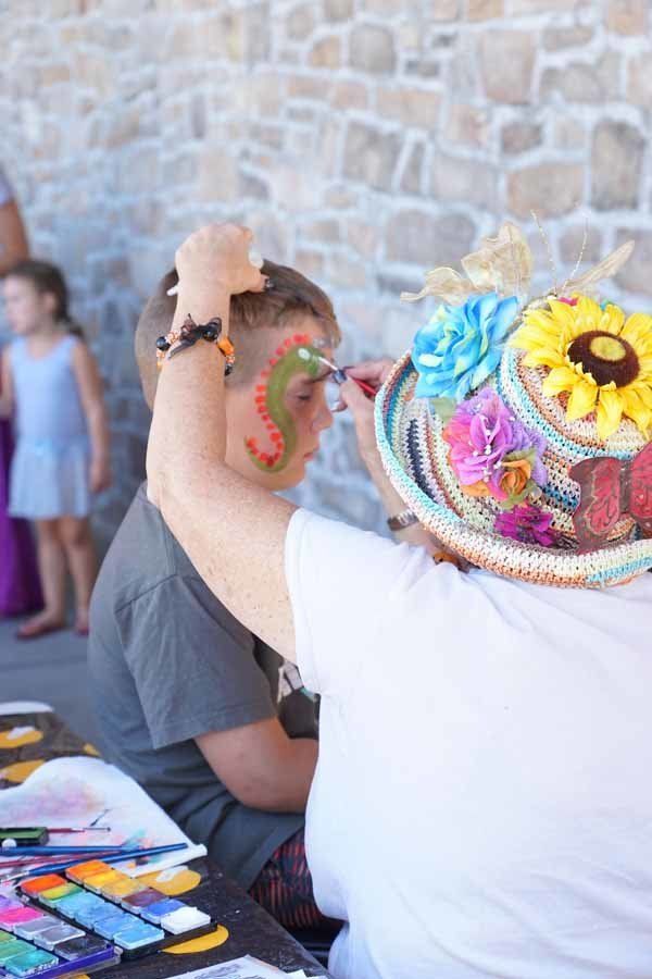 A woman is painting a child 's face with watercolors.