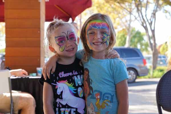 Two young girls with face paint on their faces are posing for a picture.