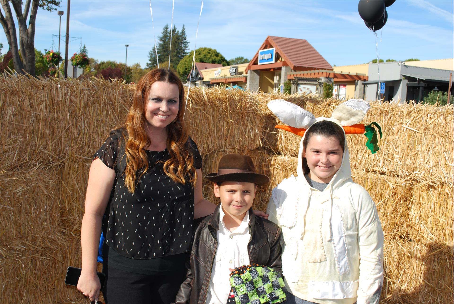 A woman and two children pose for a picture in front of hay bales