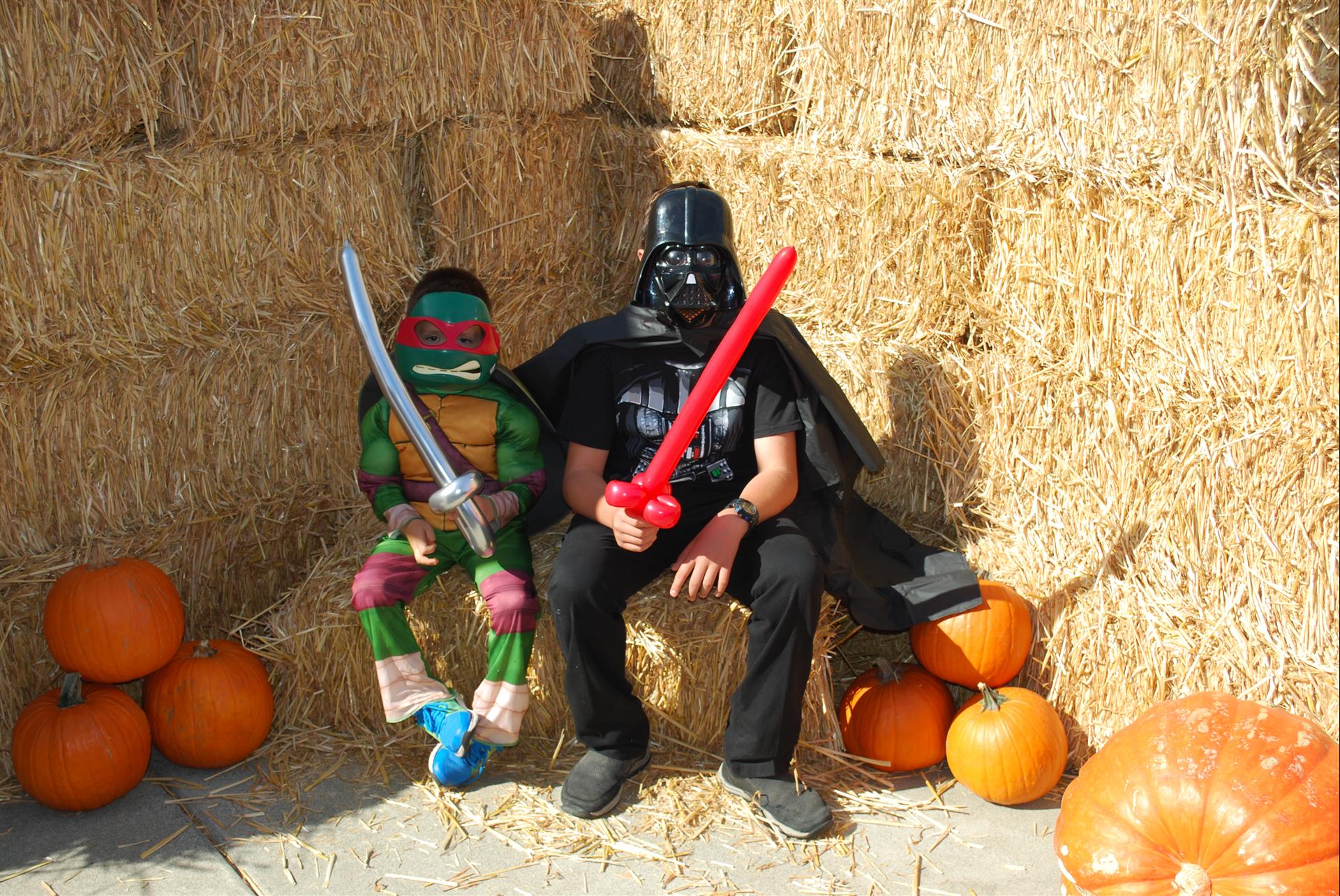 A man dressed as darth vader sits next to a teenage mutant ninja turtle