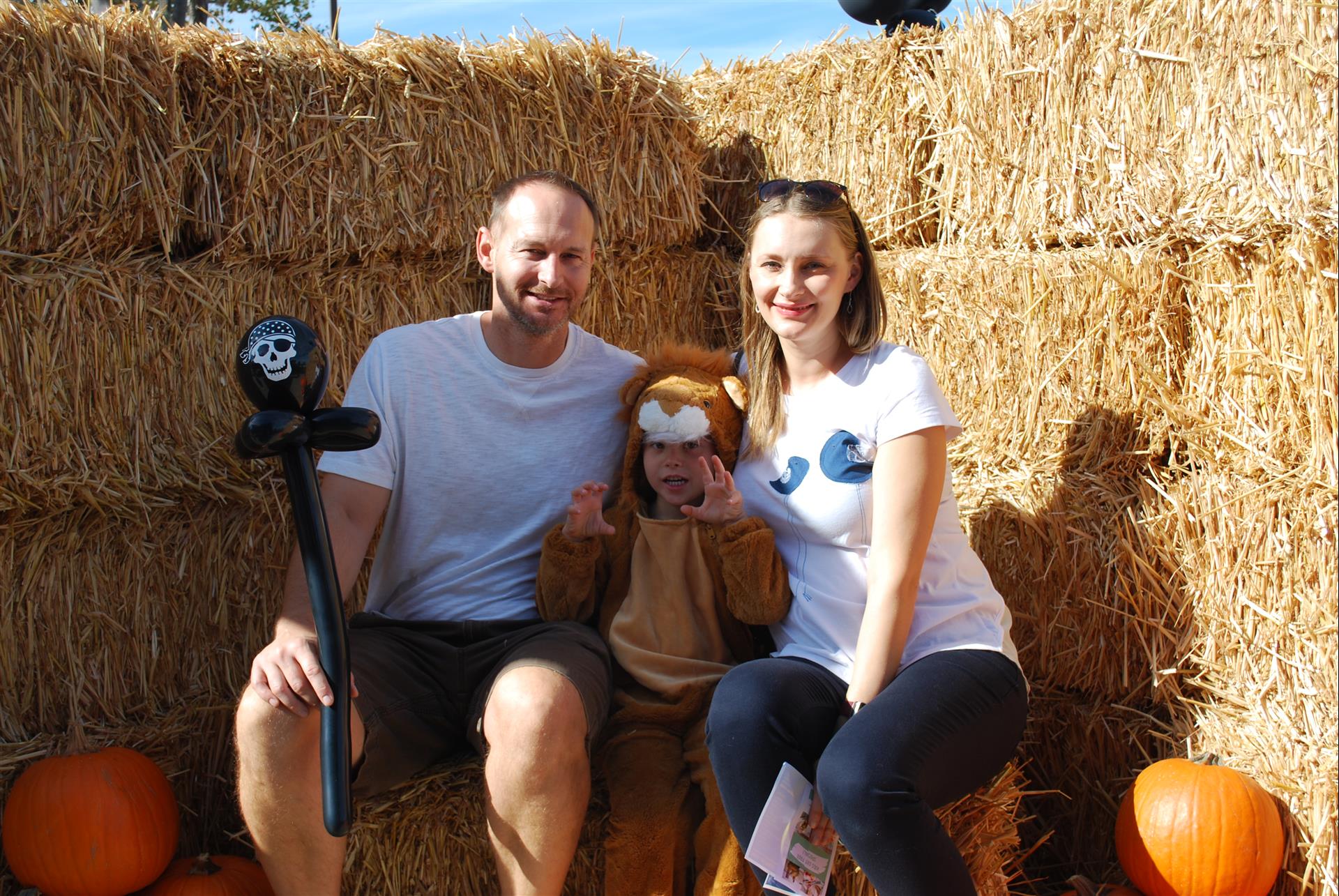 A man and a woman are posing for a picture while sitting on hay bales