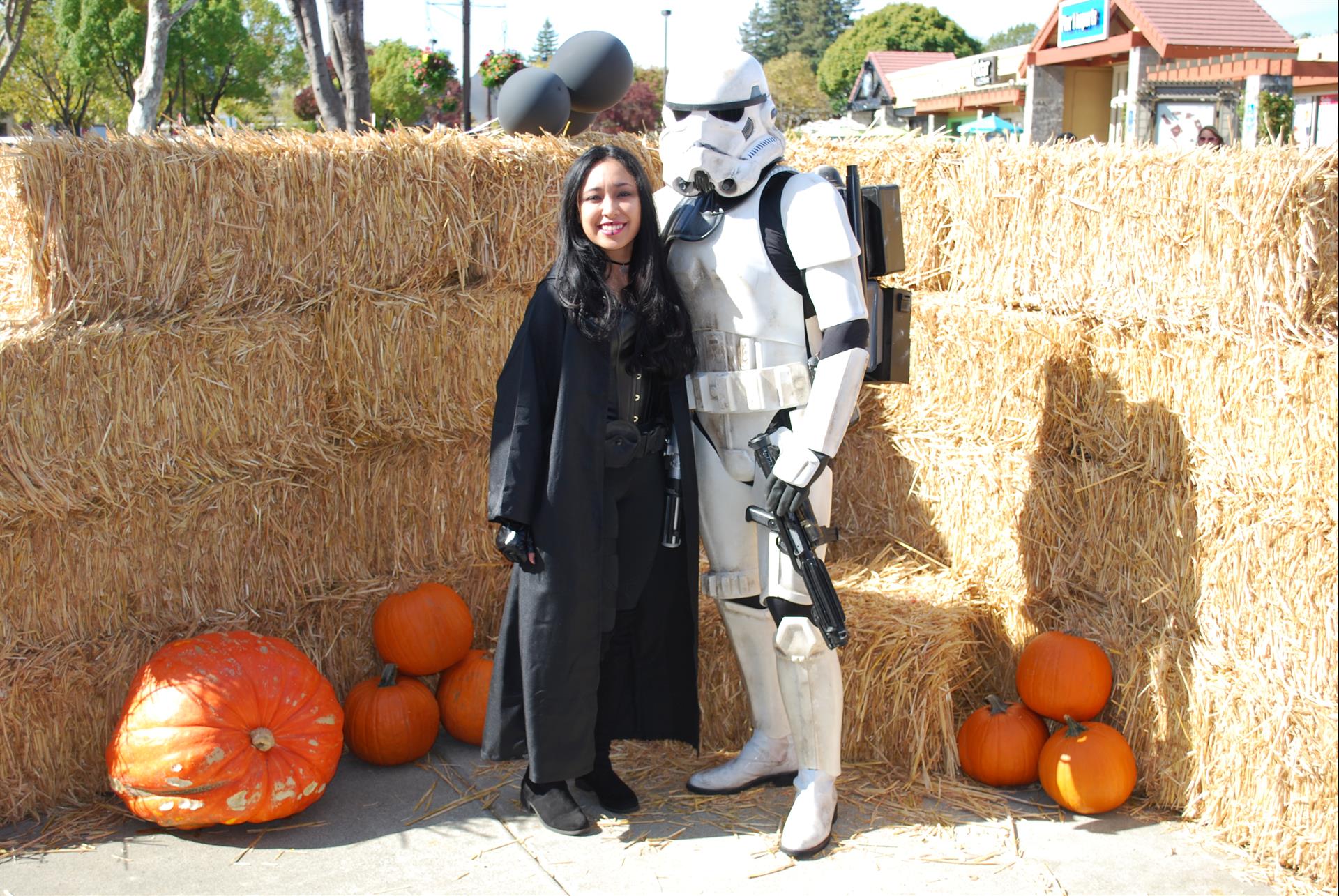 A storm trooper poses with a woman in front of hay bales and pumpkins