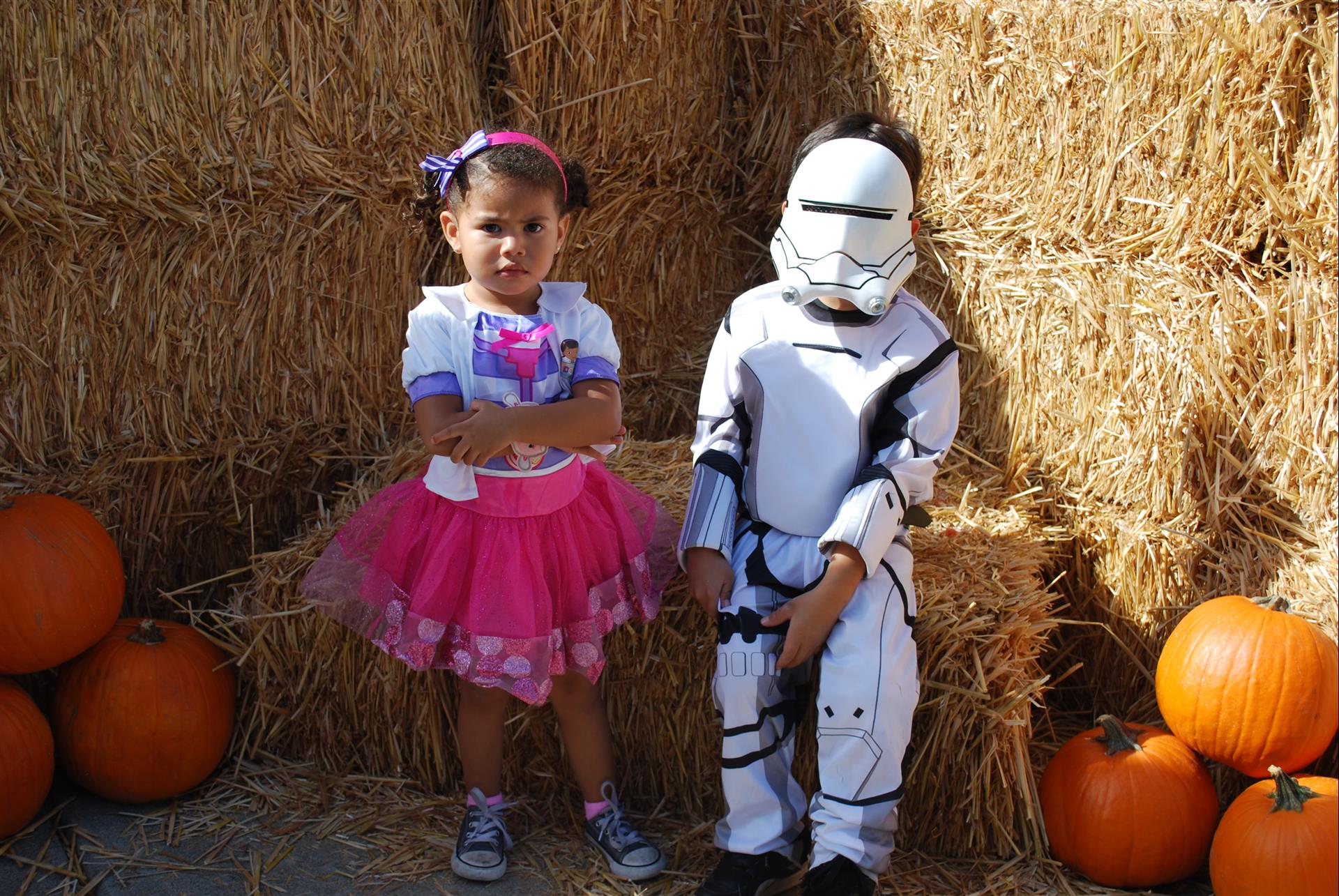 A girl in a pink tutu is standing next to a boy in a storm trooper costume
