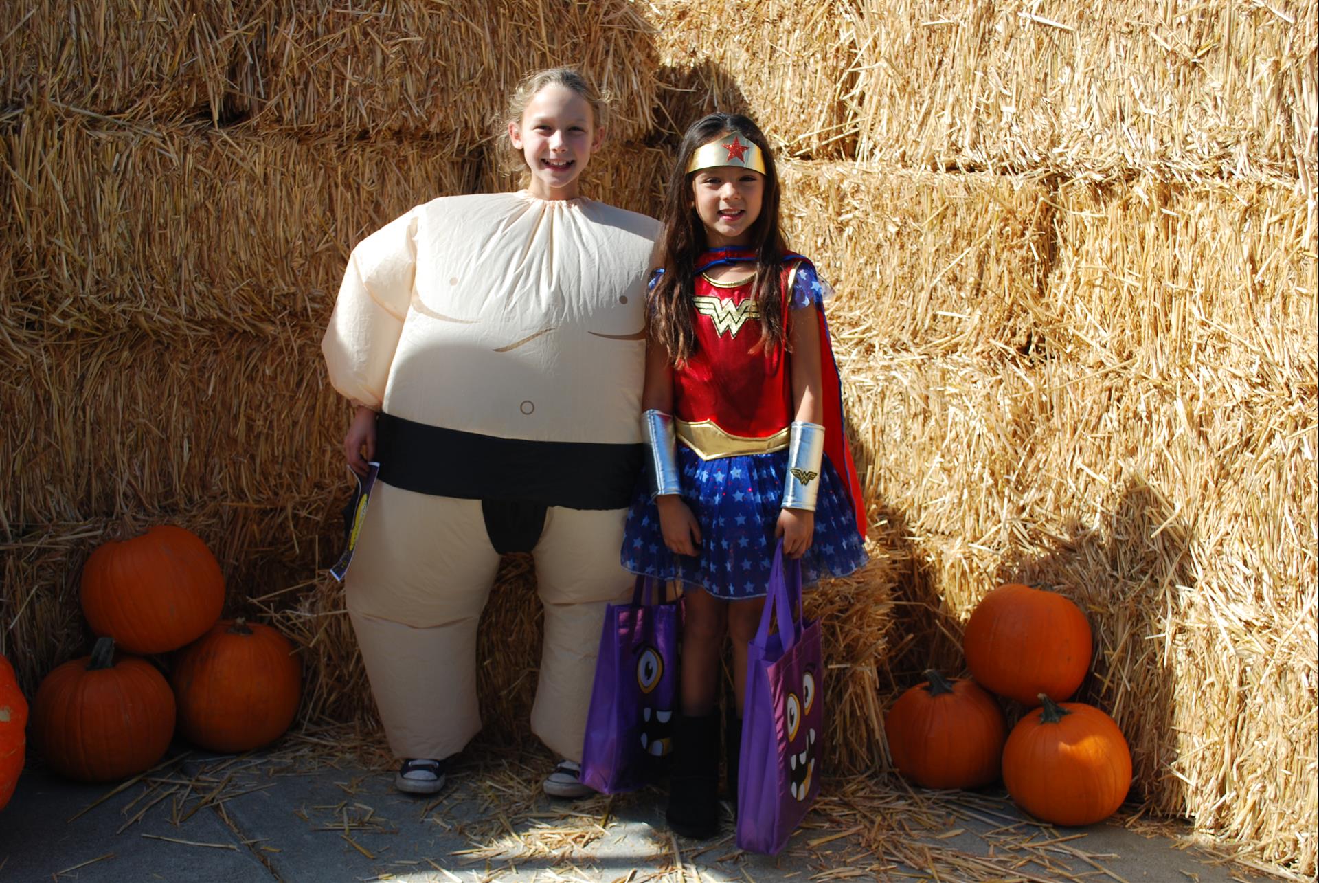 A woman dressed as wonder woman stands next to a woman dressed as a sumo wrestler.