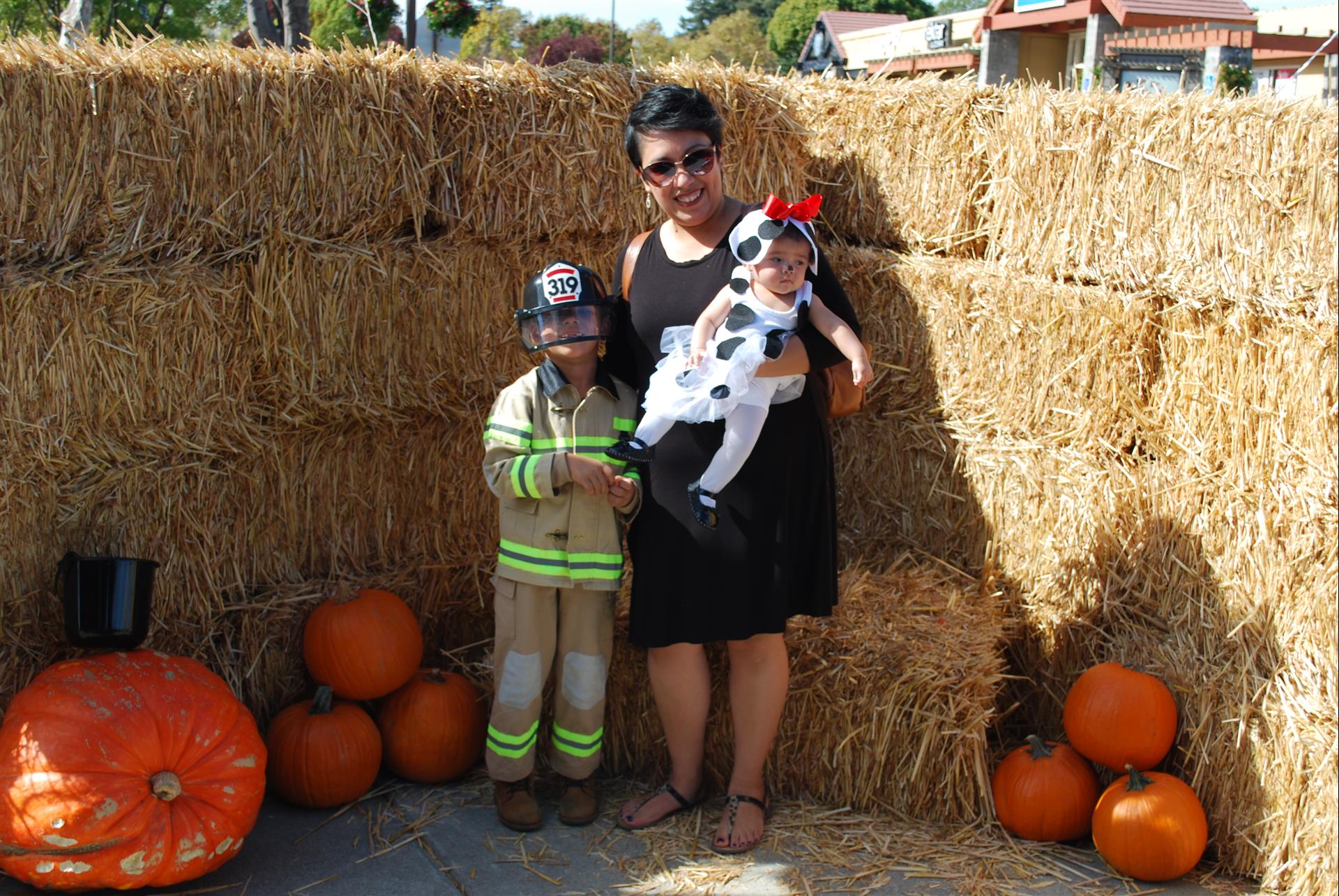 A woman holding a baby and a child in a fireman costume