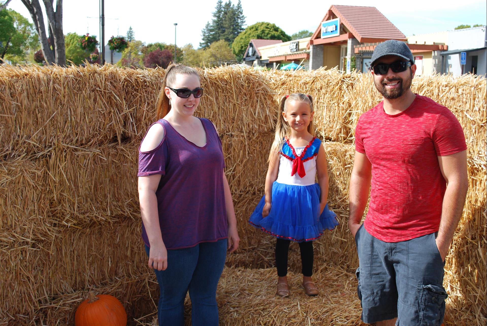 A family posing for a picture in front of hay bales