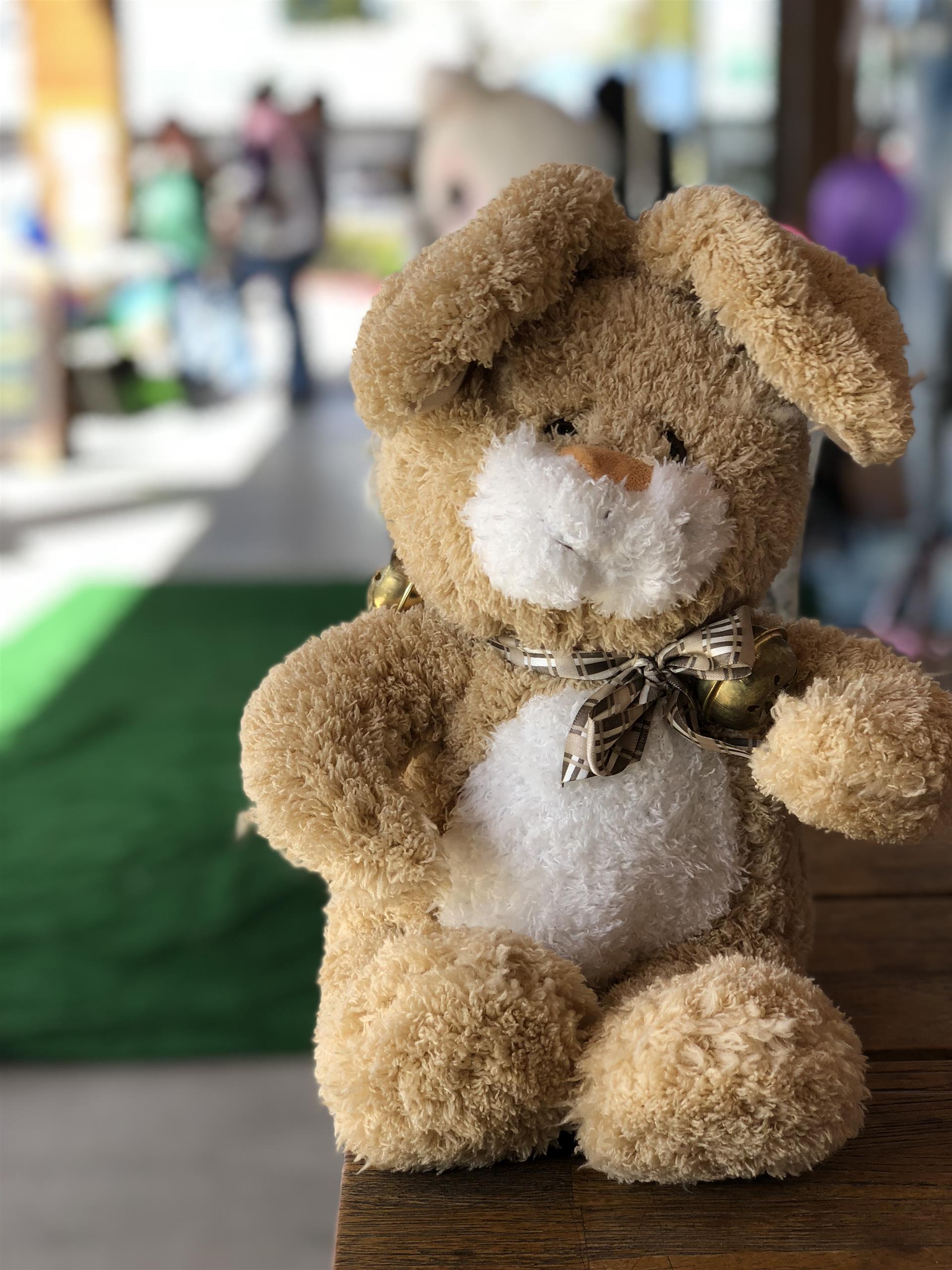 A stuffed bunny rabbit is sitting on a wooden table.