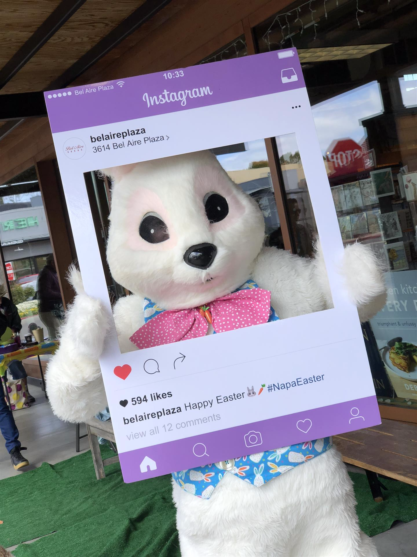 A white bunny mascot is holding a purple instagram frame.
