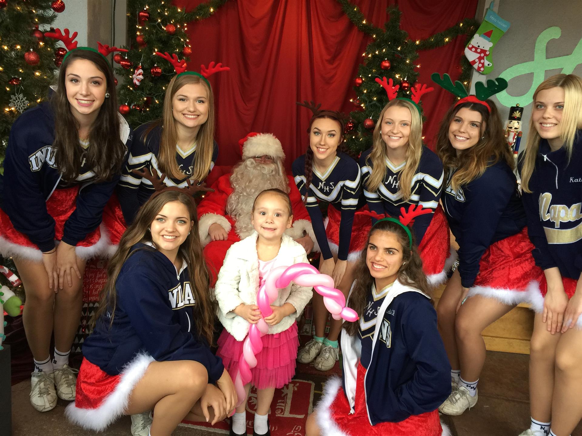 A group of girls are posing for a picture with santa claus
