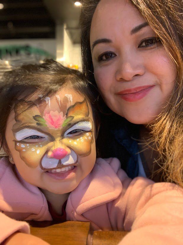 A little girl with her face painted like a deer
